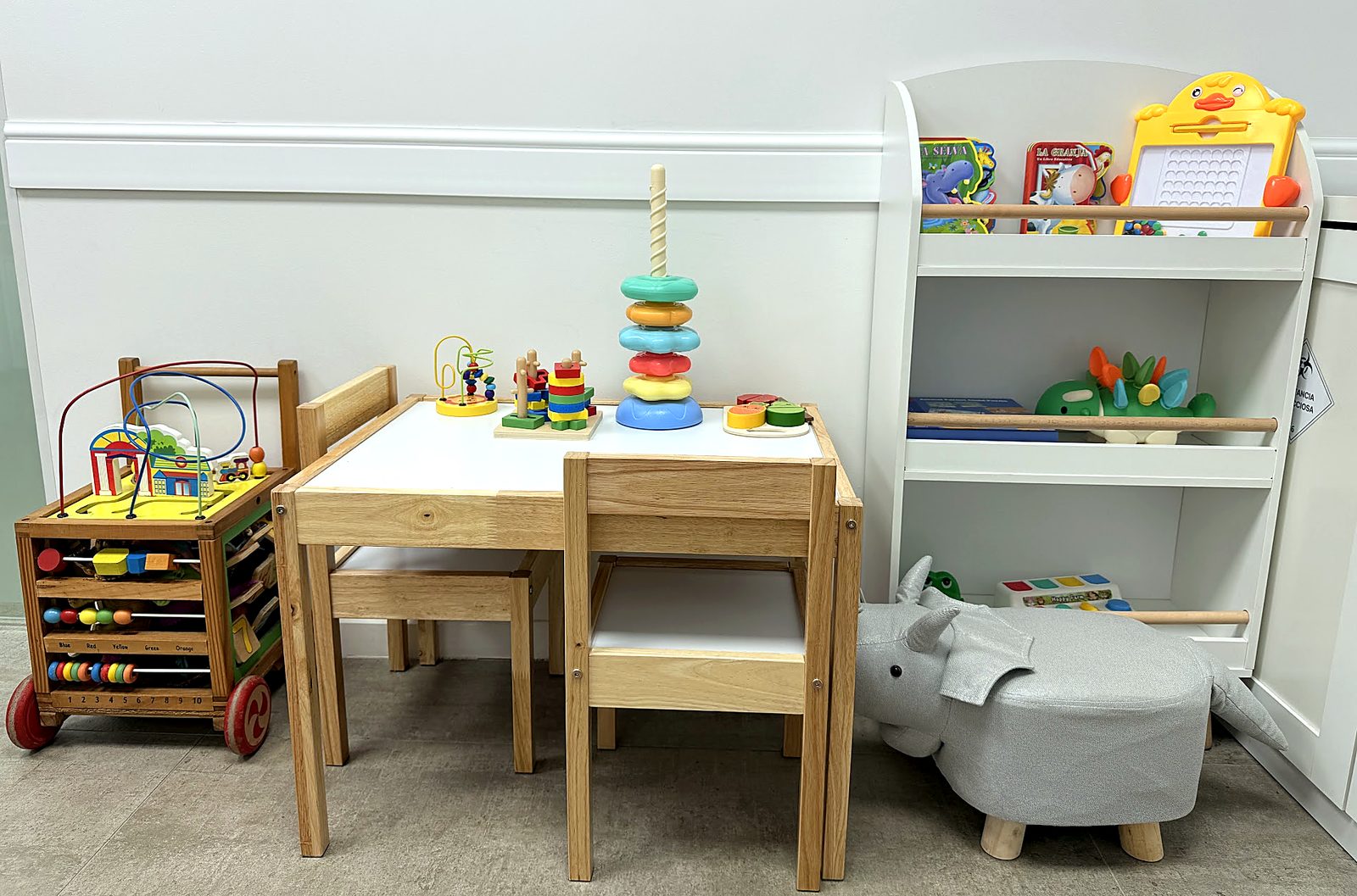 Rincón infantil de la sala de espera de Magna Clínica, con mesa, juguetes de madera y libros